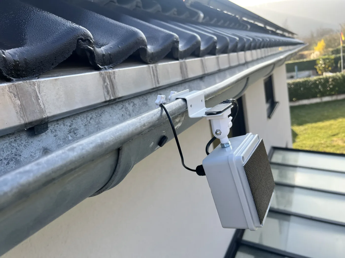 Rinnensensor an der Dachrinne eines Wohngebäudes, Blick entlang der Fassade
