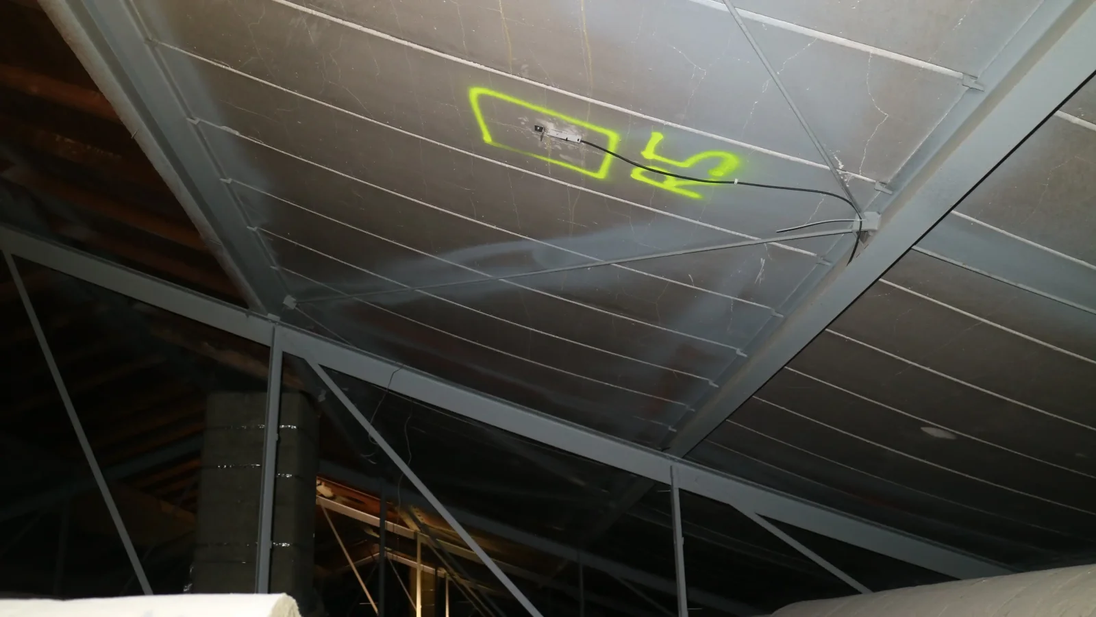 Untersicht einer Dachkonstruktion aus Betonfertigteilplatten mit gelb markiertem Messpunkt