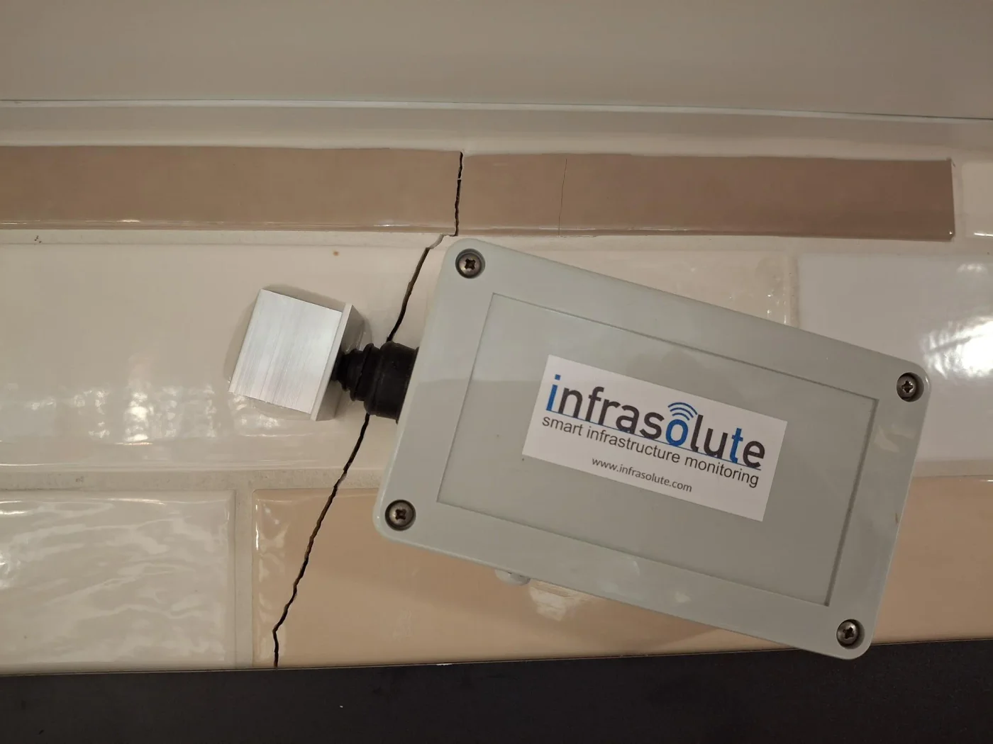 Crack sensor on a tiled wall, the crack running through the tiles