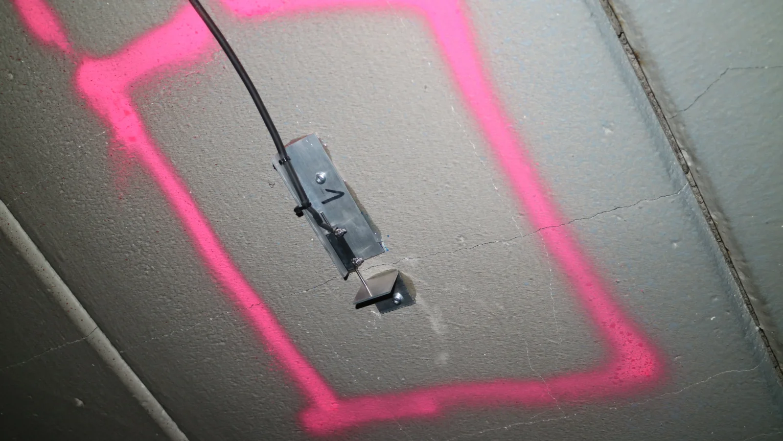 Crack sensor on a crack in a concrete ceiling marked in colour